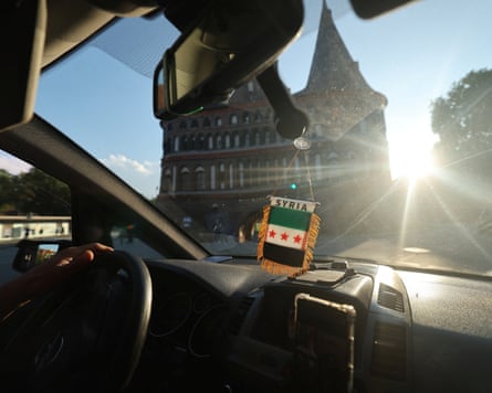 A Syrian flag hangs in a car rear-view mirror