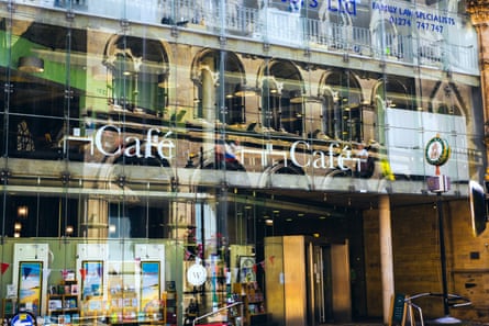 Glass frontage of Bradford’s Waterstones, showing the cafe on the first floor above book displays on the ground floor, behind reflections of historic buildings on the glass