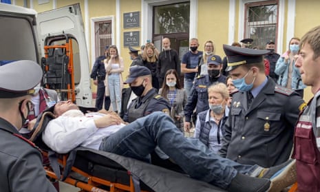 Police officers and paramedics carry Stepan Latypov, after he stabbed himself in the neck with a pen during a court hearing on 1 June.