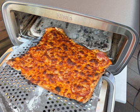 A slightly overcooked pizza on a pizza peel being taken out of the Ninja Artisan pizza oven.
