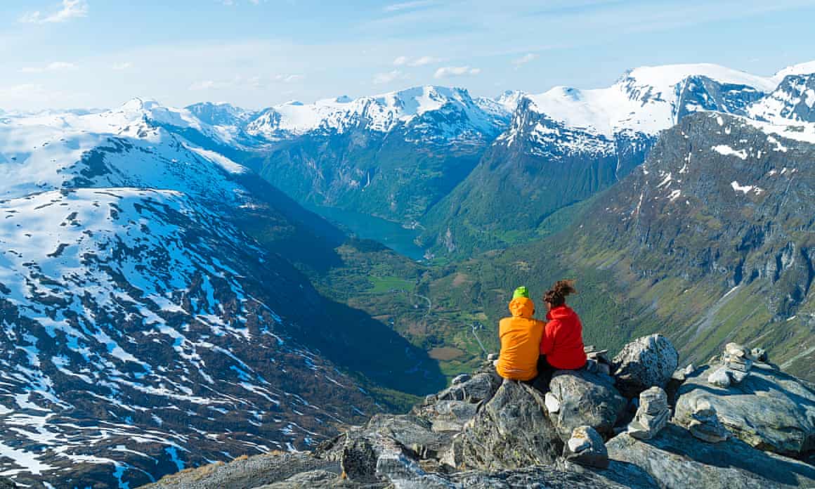 A couple looks out over snow-capped mountains in Norway.