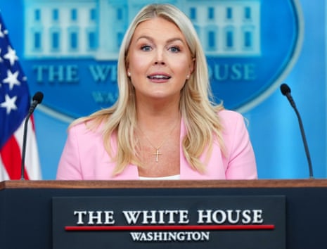 Karoline Leavitt wearing a pink blazer standing at the White House podium making an announcement.