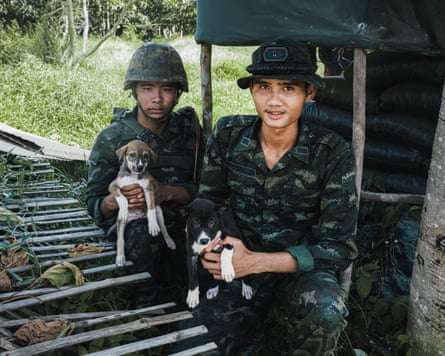 Two soldiers pose with puppies