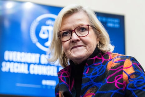 a woman in a patterned jacket and glasses looks ahead
