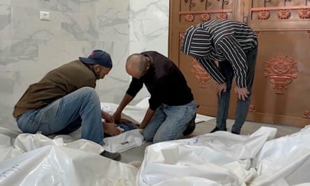 Family members unzip a body bag of children killed by Israeli airstrikes in the morgue in Khan Younis.