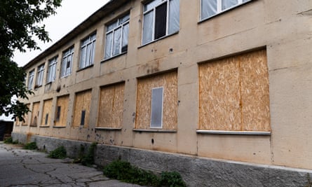 The windows of a damaged school in Kotlyareve, Mykolaiv oblast, are covered in plywood and thin layers of plastic