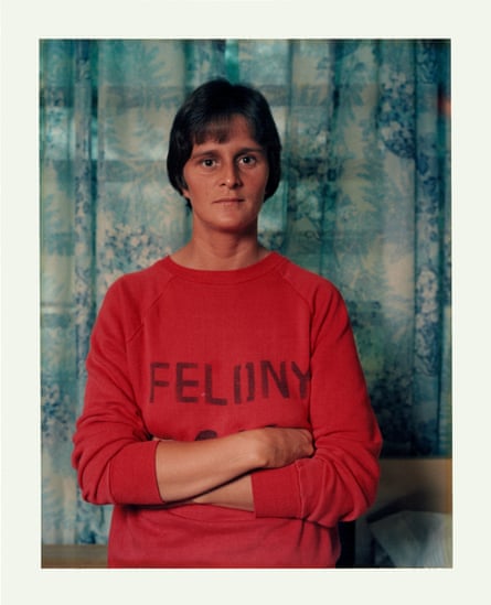 A woman in a red sweatshirt with the word ‘FELONY’ on it, standing in front of some patterned blue curtains