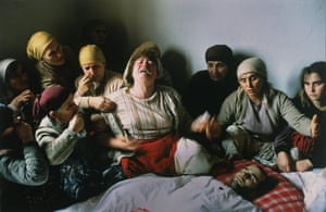 Women mourn as they sit on the floor in front of the body of a young man, in Nogovac, 28 January 1990