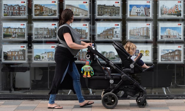A woman looks at adverts in an estate agent window in south-west London