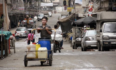 A Syrian boy pushes a cart with jerrycans filled with water in Aleppo in 2014.