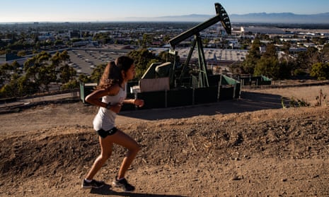 A woman runs next to a pumpjack in Los Angeles. 