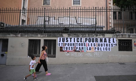 A woman and child walk past a sign in Marseille reading ‘Justice for Nahel and for all the others killed by the police’.