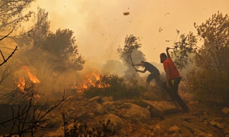 Residents help firefighters try to extinguish a wildfire burning near Athens, on 19 July 2023.
