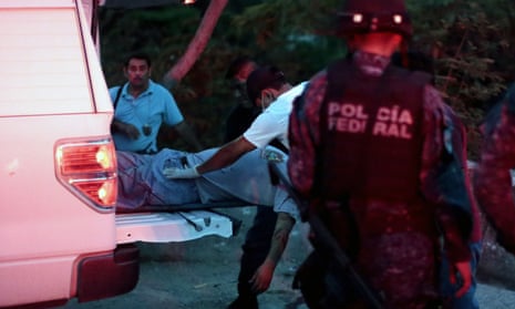 Forensic personnel carry the corpse of a person murdered by hitmen into a van in Acapulco, Guerrero.