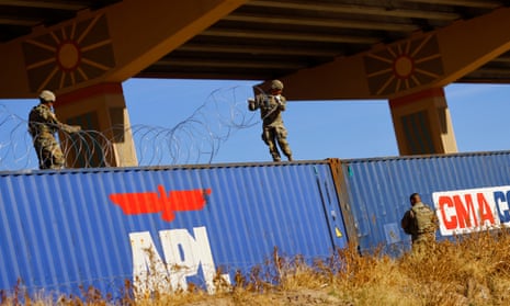 Members of the Texas national guard place razor wire on containers on the banks of the Rio Bravo river, at the US-Mexico border, on 12 January.