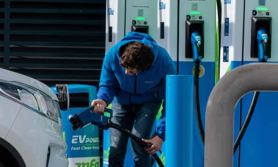 A motorist plugging in an electric vehicle on a British forecourt.