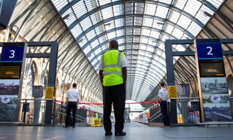 Workers stand at a closed platform at Kings Cross station, London