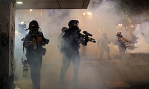 A photographer walks behind federal agents as demonstrators protest in Portland, Oregon, on 26 July.