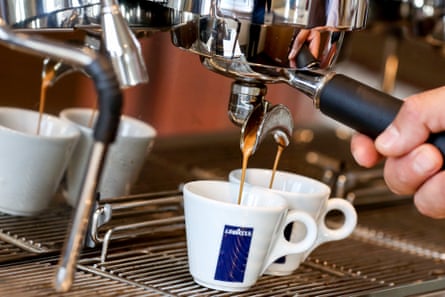 Two espressos are poured from a coffee machine.