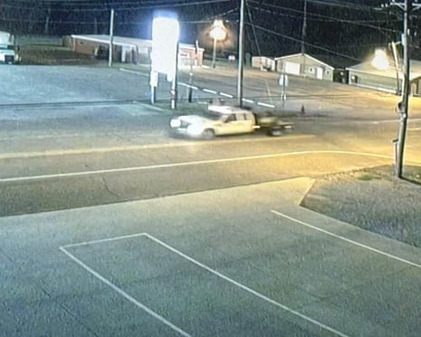 A screenshot of security camera footage showing a white truck in an empty parking lot