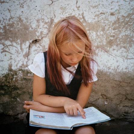 A schoolgirl reading a book on her lap.