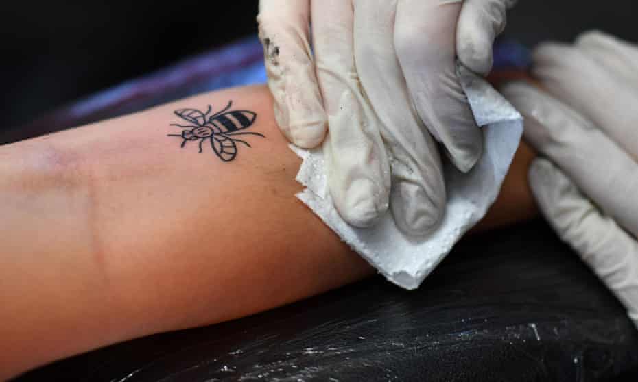 The bee symbol is tattooed on to a woman’s arm at Tattitude in Manchester.