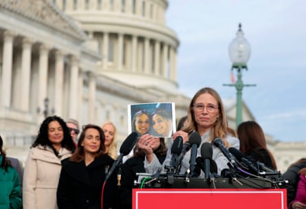 Epstein abuse survivor Annie Farmer holds up a photo of her younger self with her sister Maria Farmer during a news conference