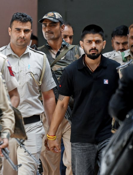 Policemen escort Lawrence Bishnoi at court, in New Delhi in 2023.