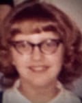 Une vieille photo d'une jeune femme avec des lunettes et une coiffure style années 60.
