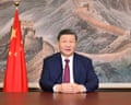 Chinese President Xi Jinping sitting at a desk in front of a painting of the Great Wall and next to a Chinese flag