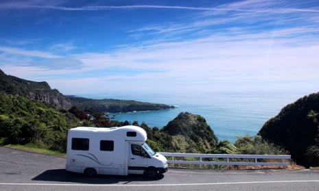 Campervan on a winding New Zealand road with sea and hills in background