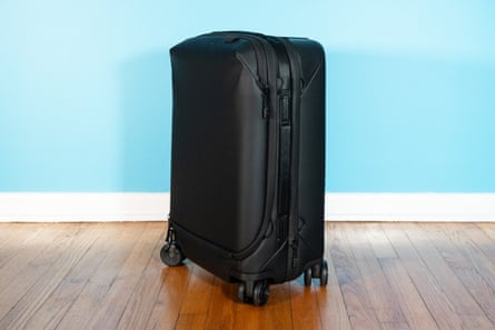 A black suitcase on wood floor in front of blue wall