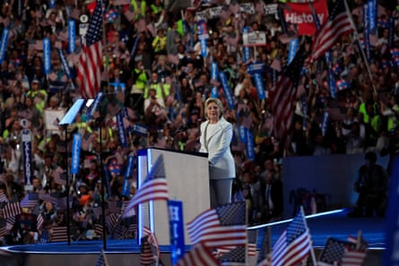 woman in white suit surrounded by crowds waving american flags