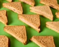Ham and cheese sandwiches on whole wheat bread arranged on green surface.