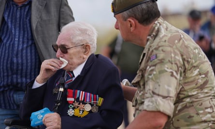Veteran Donald Jones with medals lining his cost, puts a hanky to his mouth and is comforted by a member of the Royal British Legion as he returns to Sword beach in Normandy, France, where he landed on D-day