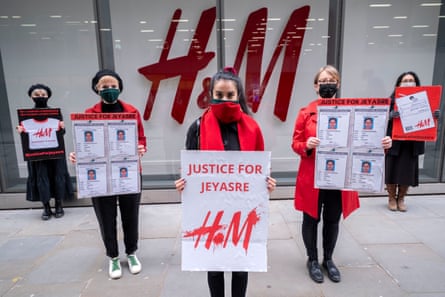 A group of female protesters wearing red and black hold red and black placards saying ‘H&M Justice for Jeyasre’.