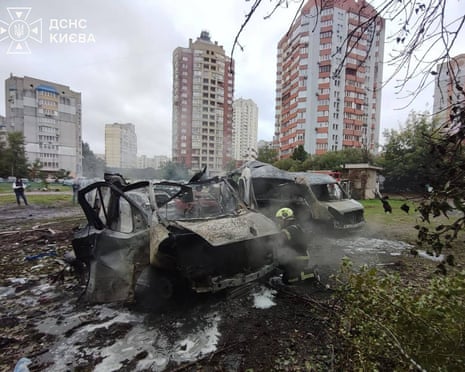 A Ukrainian rescuer works next to burnt-out cars at the site of an air attack in Kyiv, amid the Russian invasion of Ukraine.