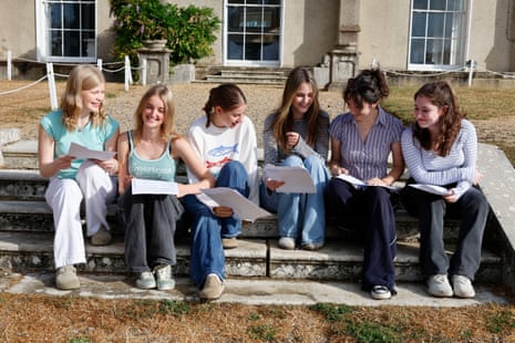Six students sat on a bench looking at each other’s results papers.