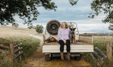 Alice Armitage wears a lilac sweater and is sitting in the tray of a ute with legs dangling off the back. Her dog is sitting next to her