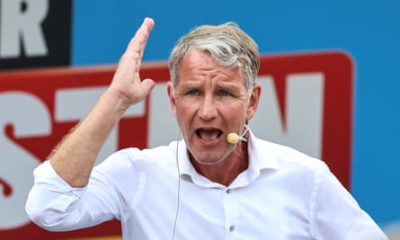Björn Höcke gestures while speaking in front of a campaign poster
