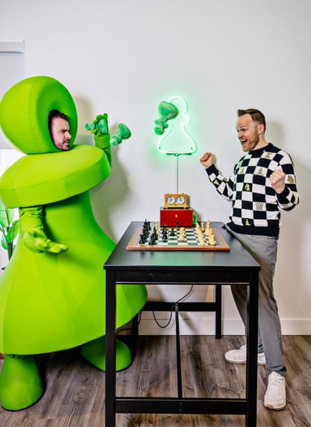 Danny Rensch, wearing a green suit in the sham of a chess piece, at Chess.com, where he is chief chess officer, with its CEO, Erik Allebest