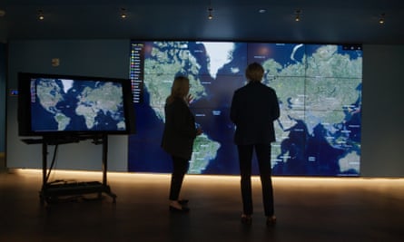 film still of two people standing in front of big map of the world
