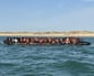 A crowded inflatable boat carries dozens of migrants in orange life vests near Berck's coast