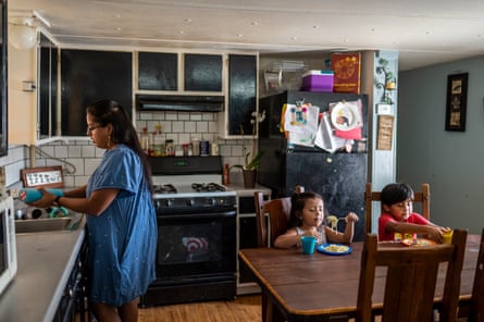 Paola Valdez-Lopez cleans while her kids, Alycia, five, and Matias, six, eat dinner in Austin.
