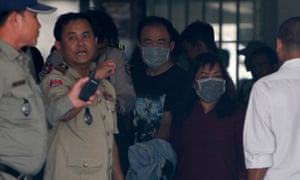 People suspected of being intermediaries for surrogacy are escorted by police officers through the municipal court in Phnom Penh