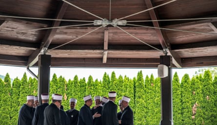 A group of men wearing formal clothes greet each other warmly.