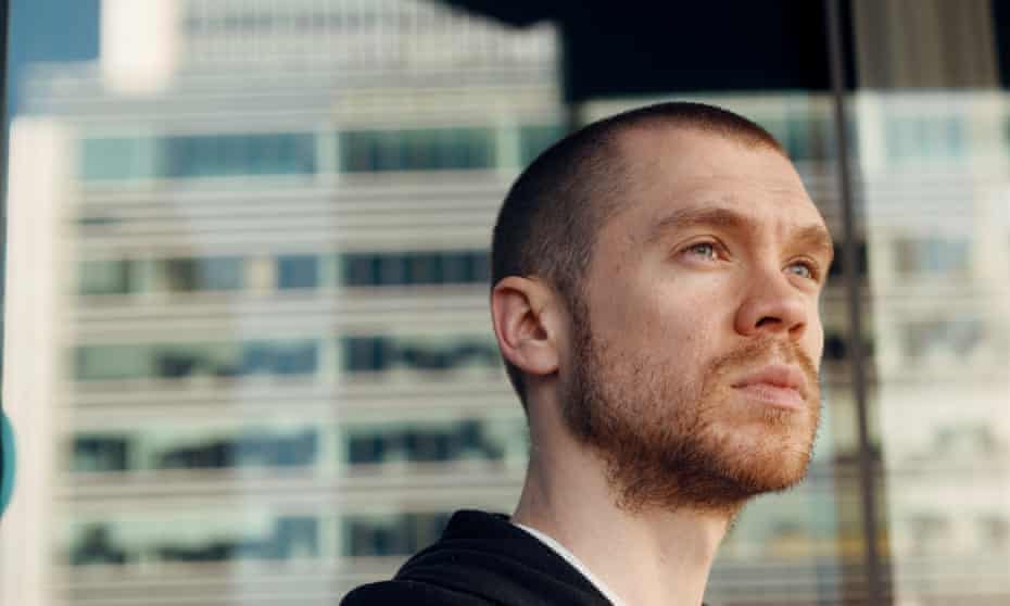 Head and shoulders portrait of Gary Stevenson against the backdrop of a skyscraper looking off camera