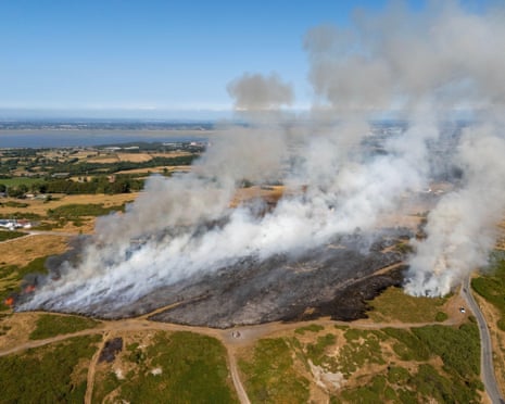 Smoke billows up from a wildfire in a rural landscape