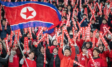 Fans wearing red wave a big North Korean flag