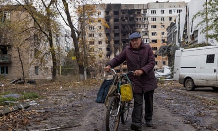 A resident wheels is bicycle in front of damaged blocks of flats in Avdiivka.